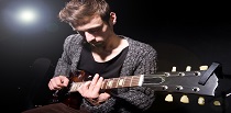 Mand der spiller guitar og link til siden Tilskud og puljer på kulturområdet